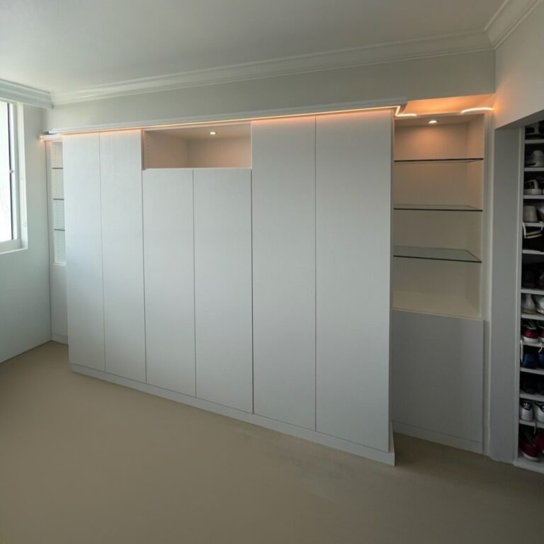 Modern Custom Reach In Closet With White Cabinetry, Integrated Shelving, And Soft Led Lighting.
