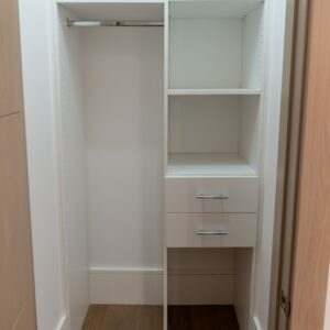 Small reach-in closet with custom shelving, hanging space, and compact drawers.