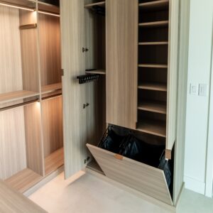 Small walk-in closet with multifunctional storage elements, adjustable shelving, and tilt-out hamper.