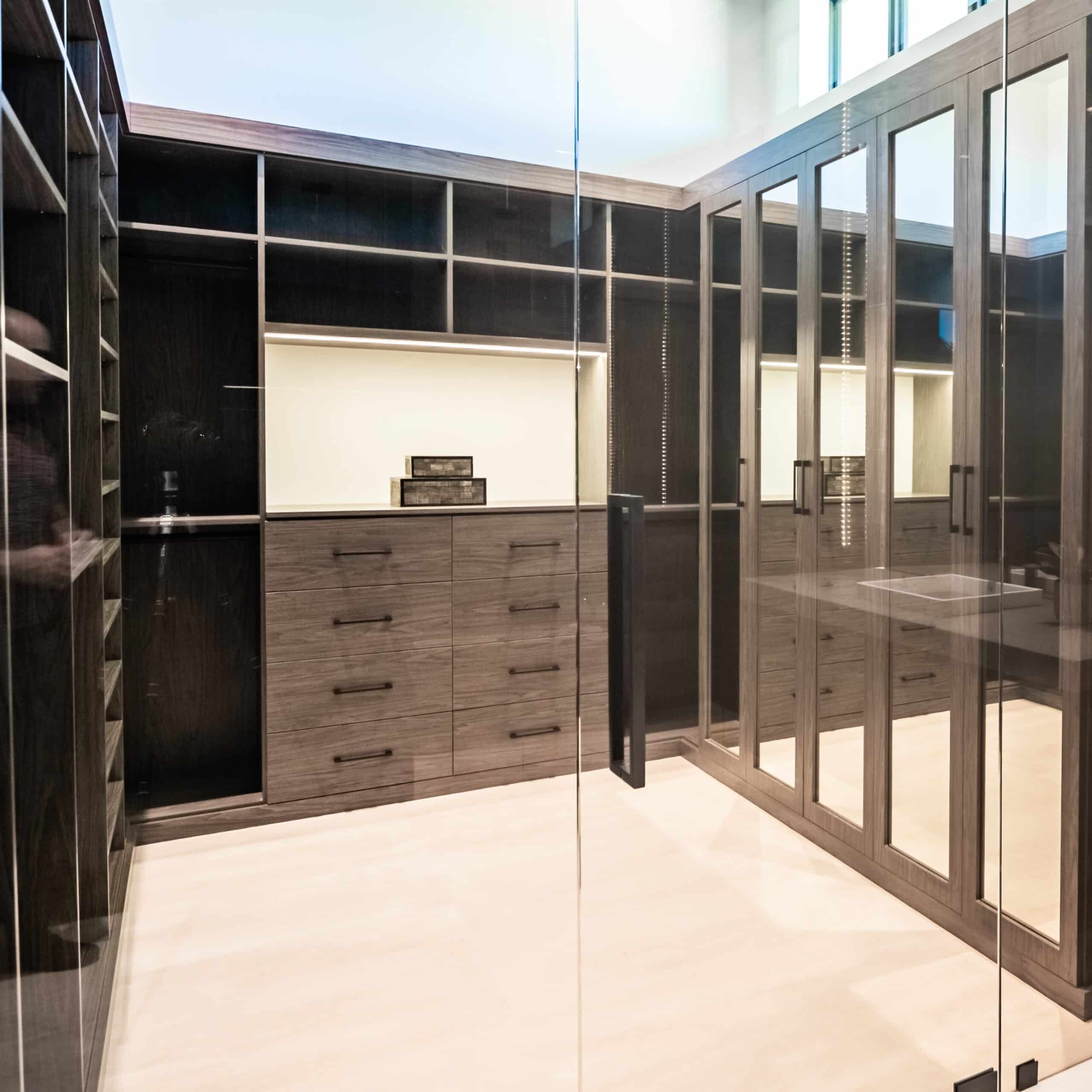 Modern custom closet with dark wood shelving and mirrored doors.