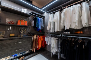 Modern walk-in closet in dark wood finish with integrated lighting system