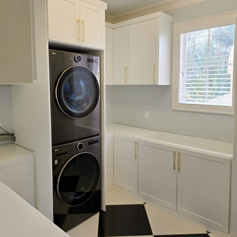 Compact Laundry Room With Stacked Washer And Dryer, Upper Cabinets, And Integrated Countertop.