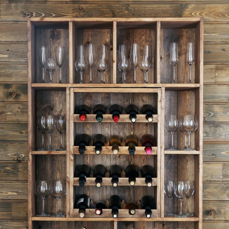 Shelving With Wine Bottles And Glasses On Wooden Wall Background