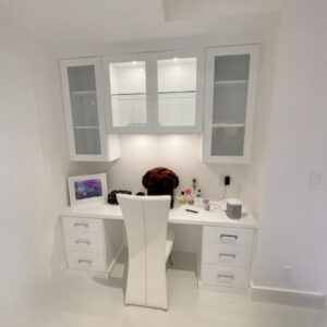 Small modern home office with a white desk and glass cabinets.