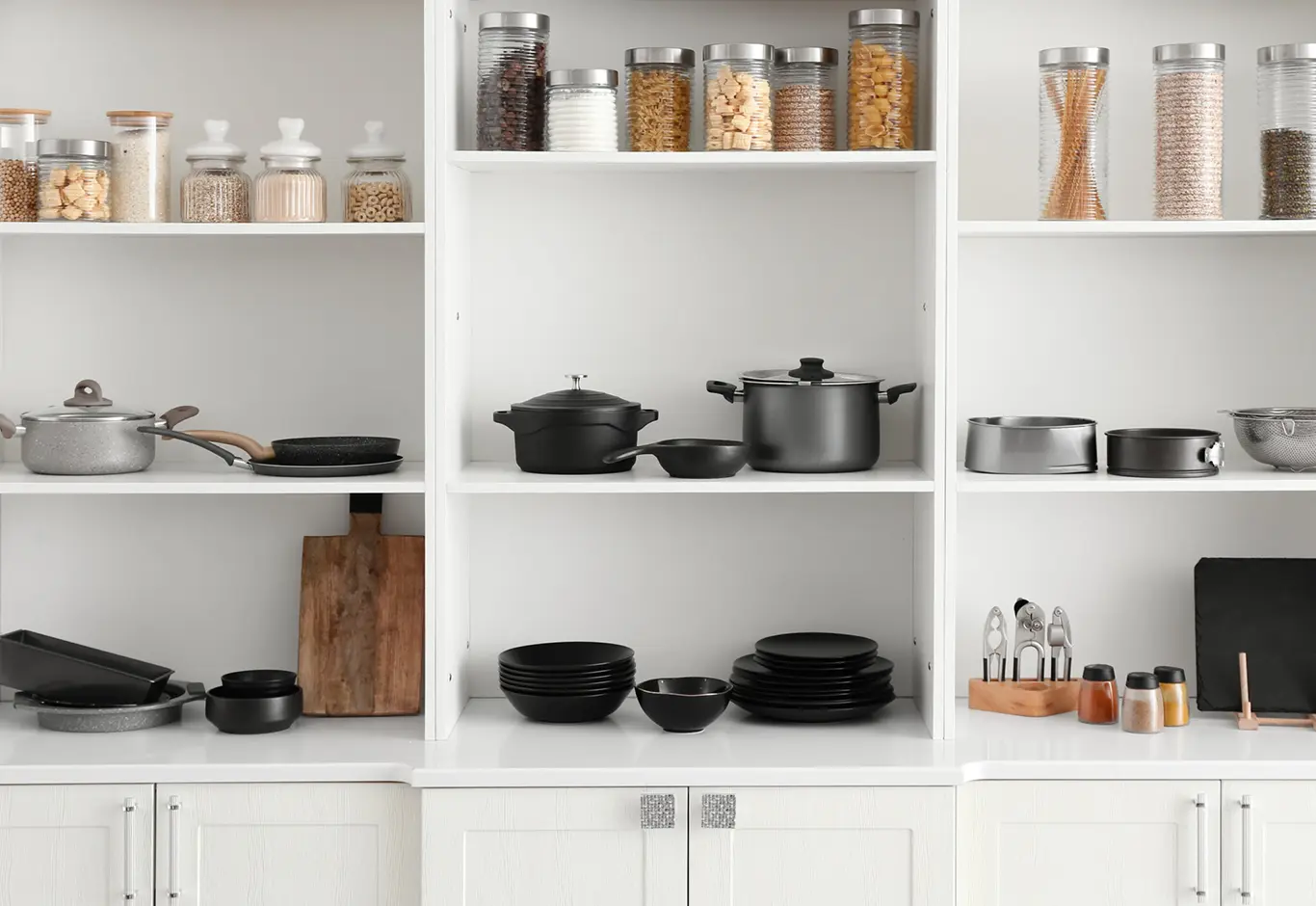 Modern Pantry With White Shelves, Glass Jars, Cookware, And Neatly Arranged Kitchen Items For Efficient Storage.